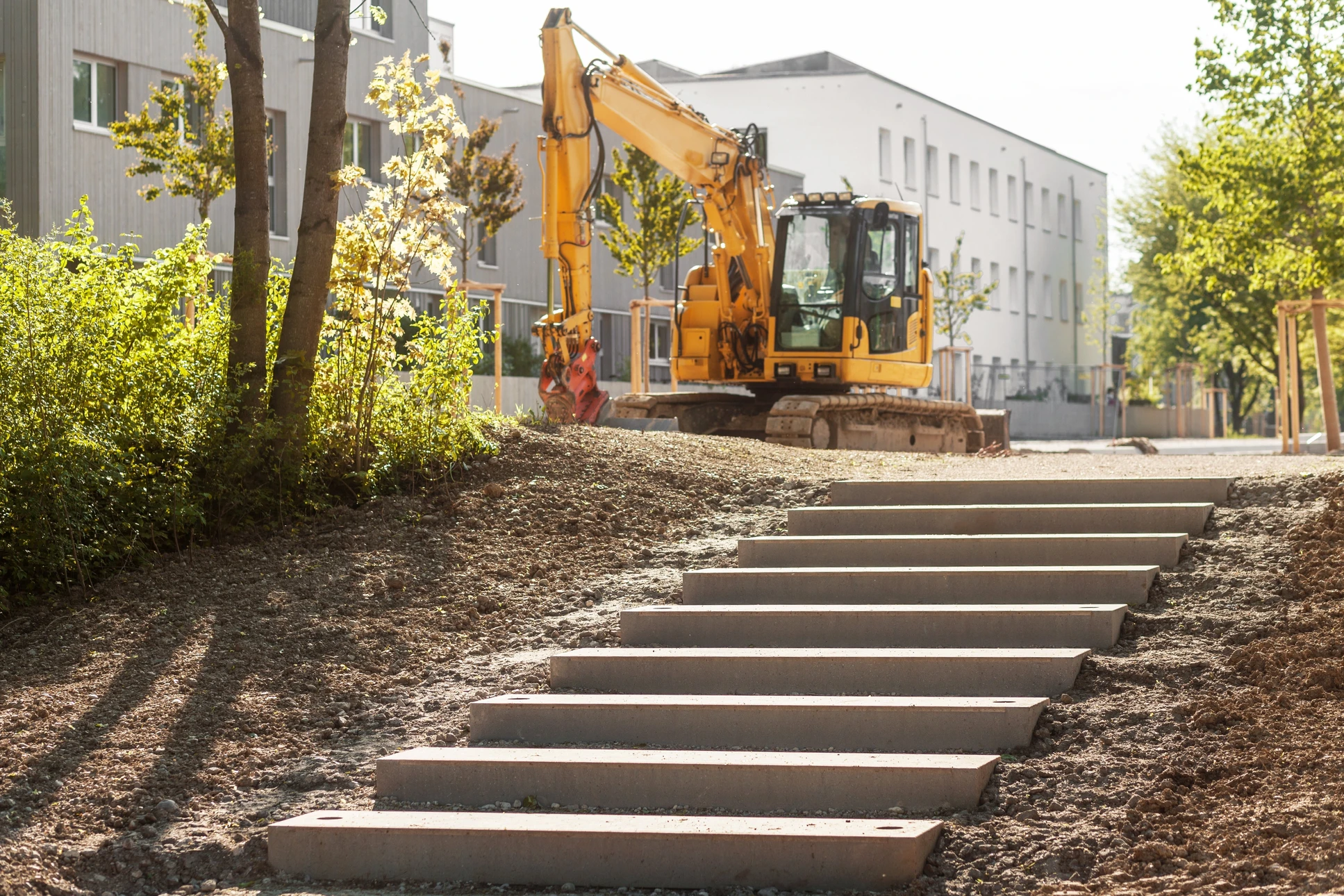 Chantier de construction extérieur avec pelleteuse hydraulique sur chenilles procédant à des travaux de terrassement
