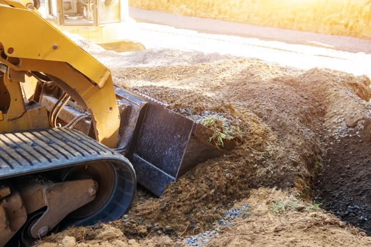 Chantier de terrassement en extérieur avec pelleteuse hydraulique chargeant des matériaux dans un camion-benne
