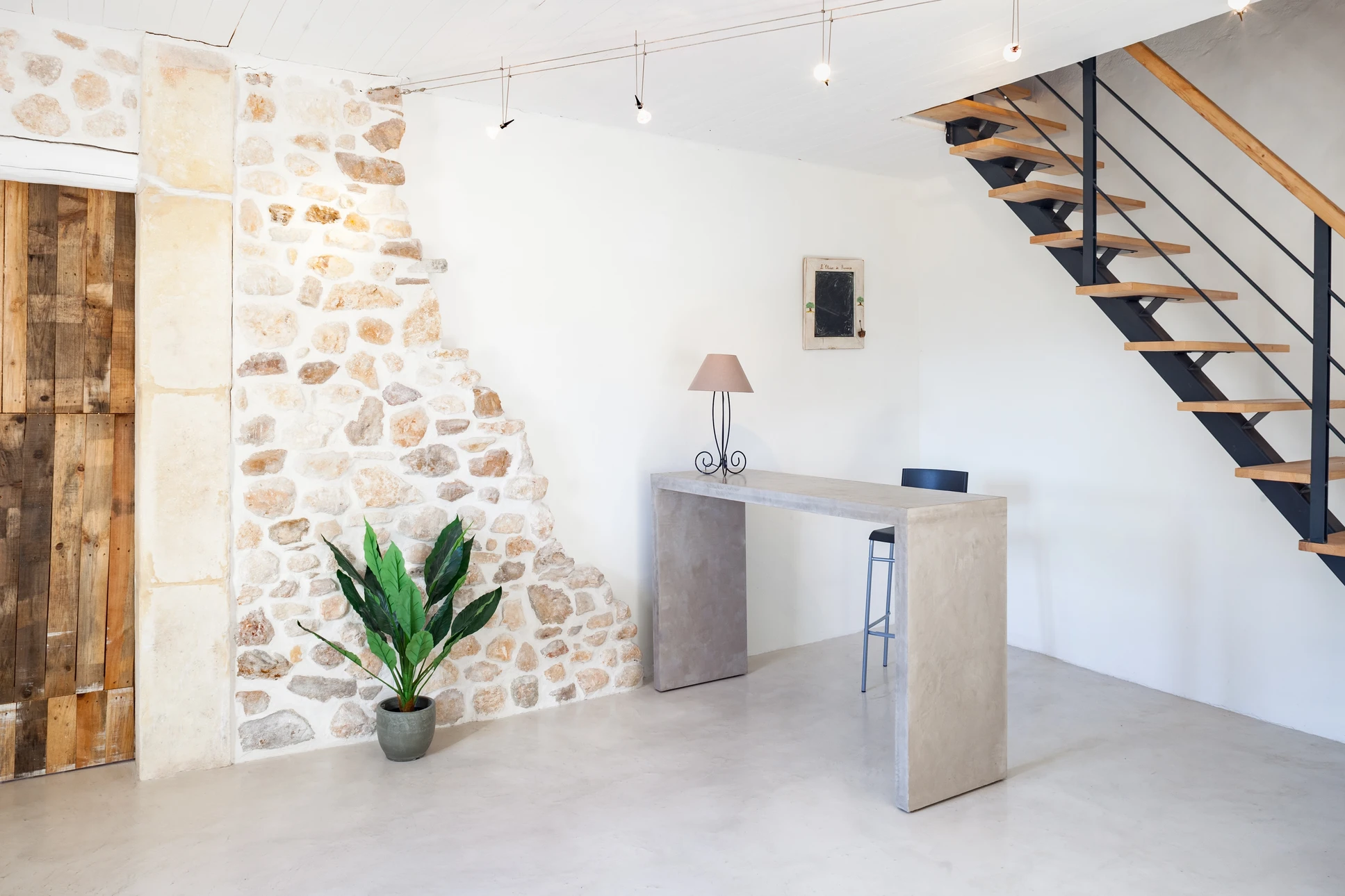 Salon intérieur d'une maison rénovée avec murs peints de couleur claire, sol en carrelage moderne, mobilier contemporain, éclairage chaleureux et fenêtre apportant la lumière naturelle, créant une atmosphère confortable et accueillante.