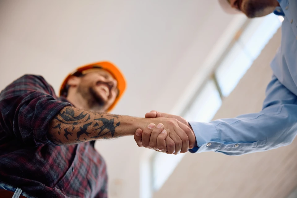 Deux hommes se serrent la main dans un espace intérieur en rénovation